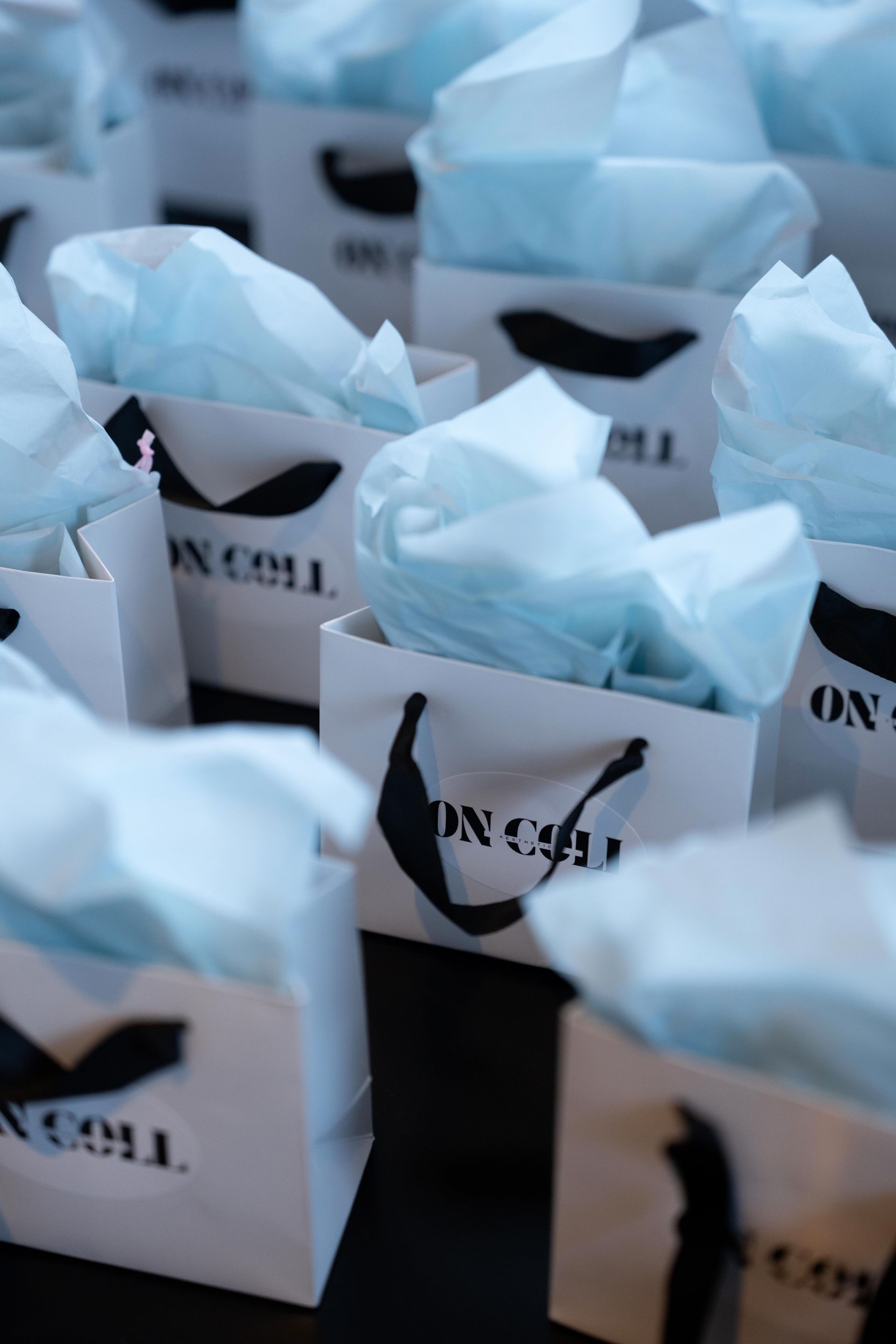 Rows of small white gift boxes with light blue tissue paper