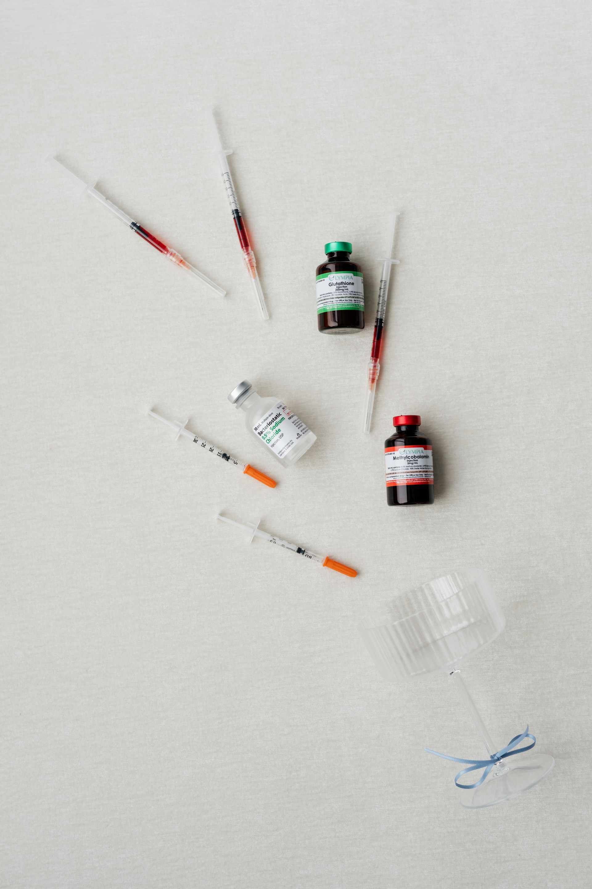 Assorted medical vials and syringes scattered on a white surface