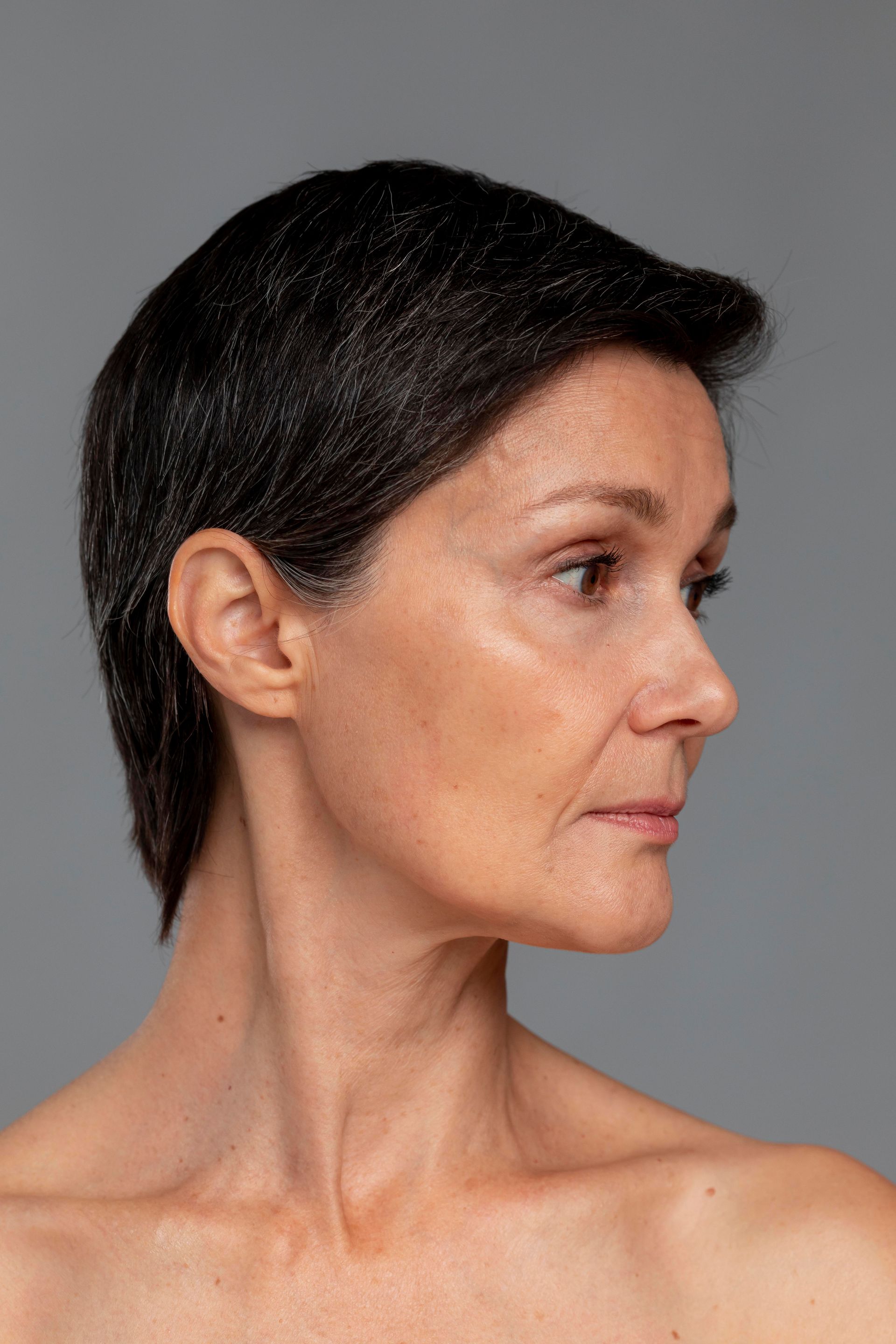 Side profile of a person with short dark hair, looking to the right against a gray background.