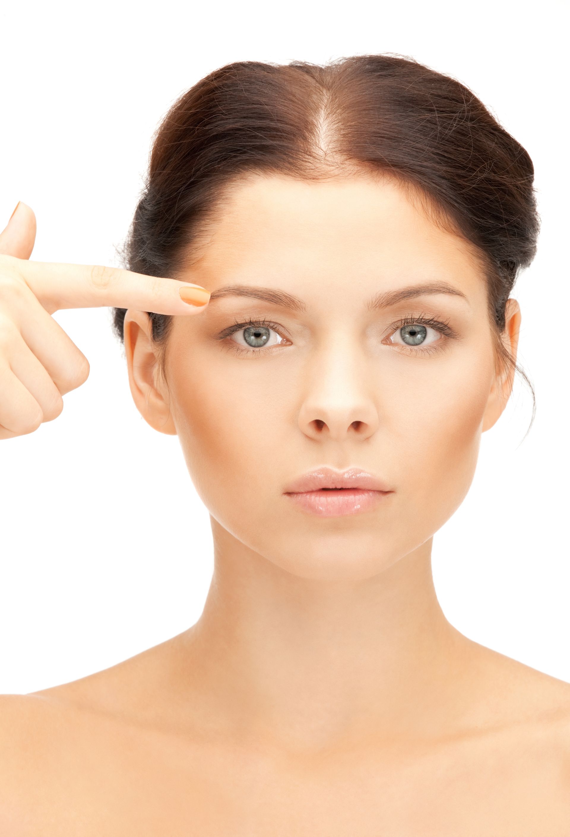 Portrait of a woman pointing to her eyebrow against a white background