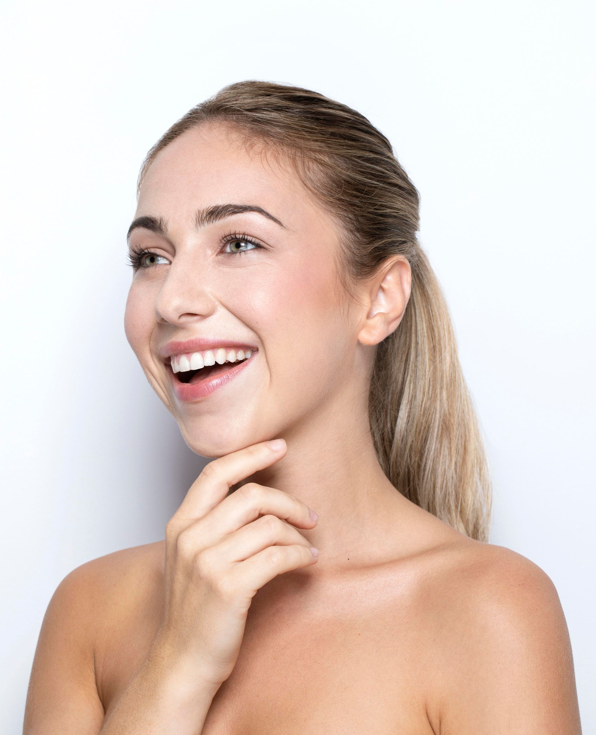 Smiling woman with hand on chin against a light background