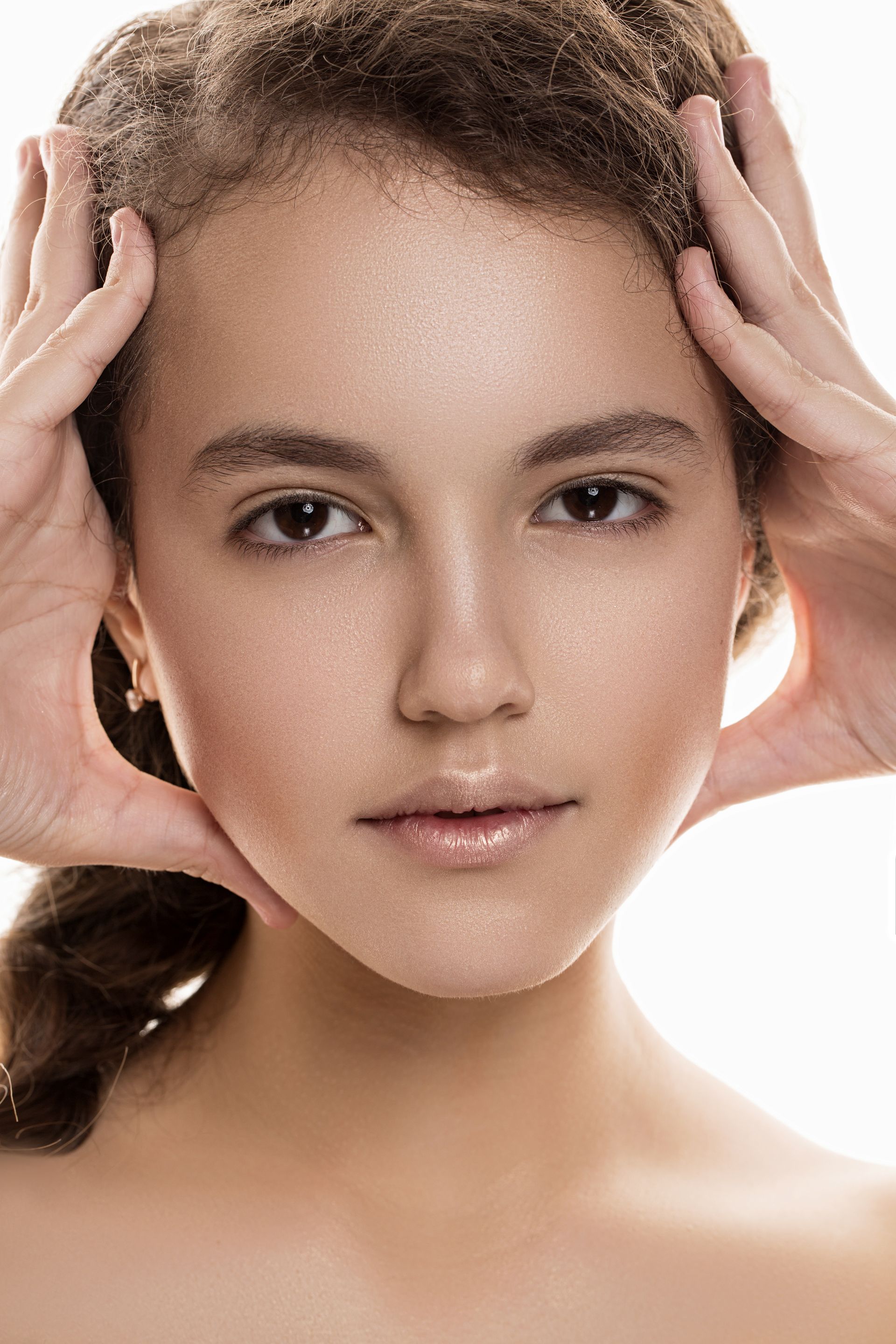 Close-up portrait of a person with hands framing their face against a white background