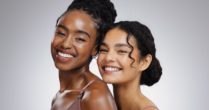 Two smiling models posing closely against a light gray background