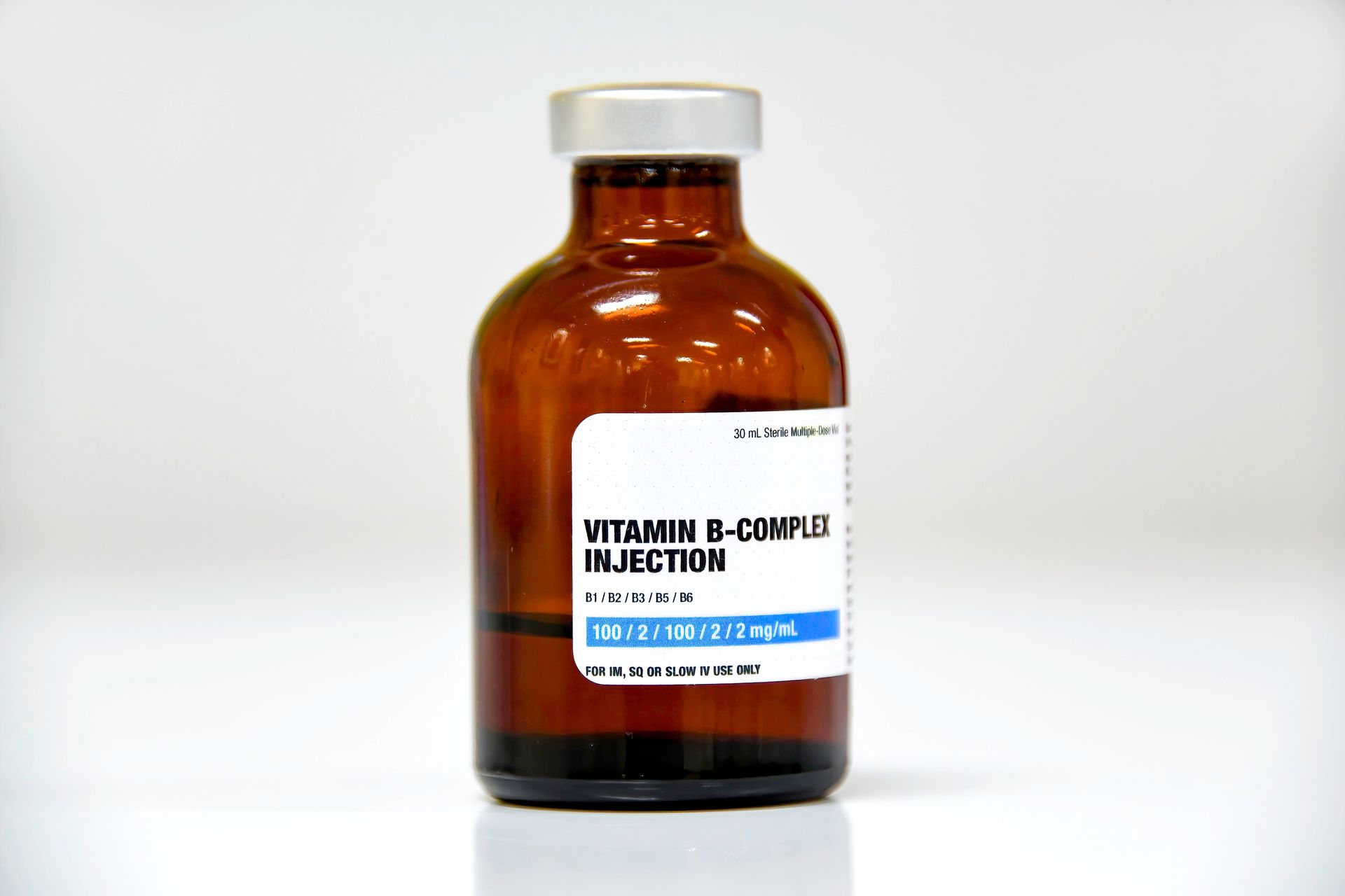 Amber vial labeled “Vitamin B-Complex Injection” with a white cap on a white background