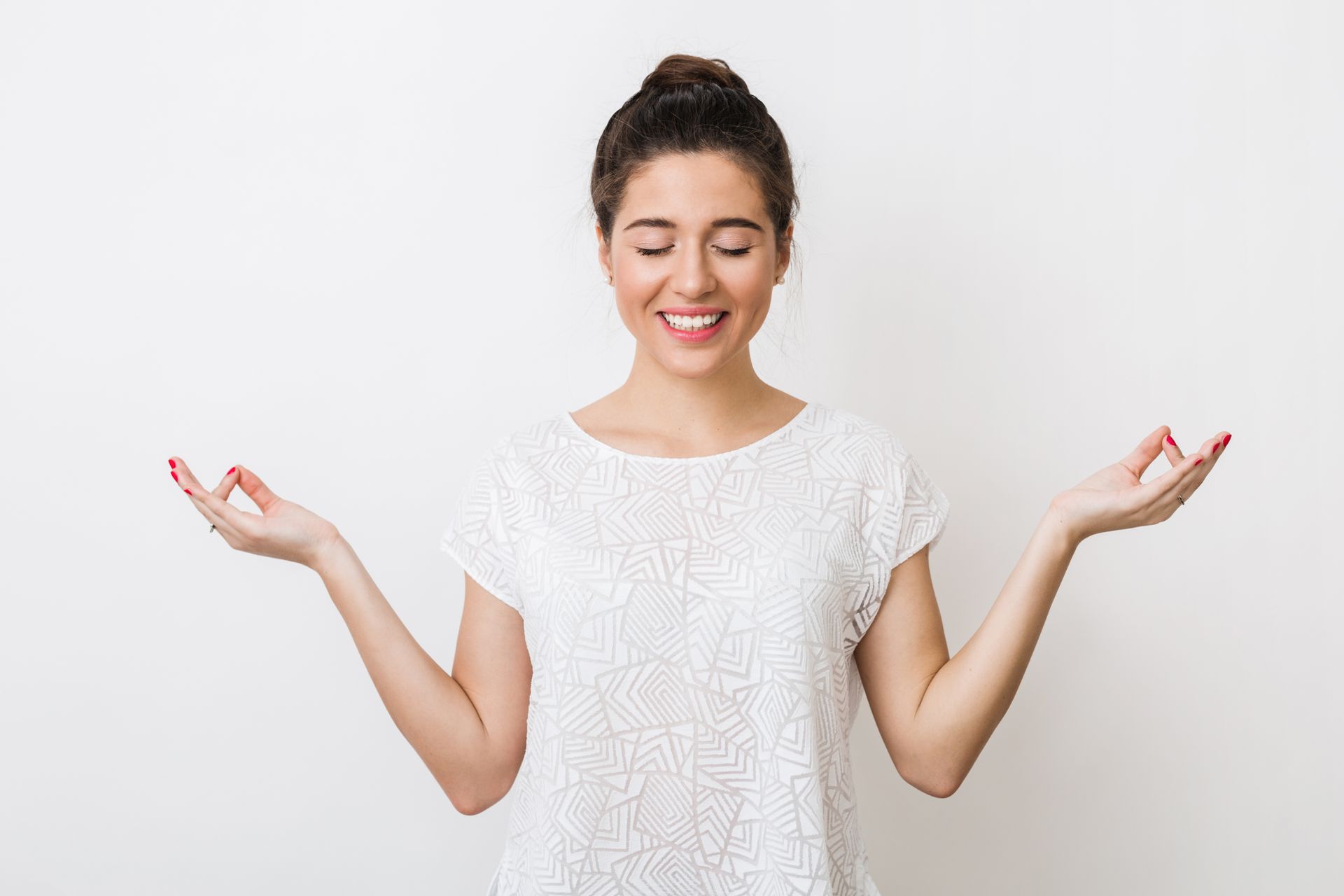 Smiling woman in a white shirt with arms raised against a plain background