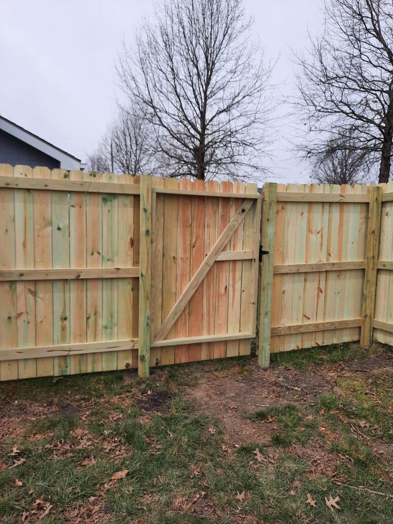 A wooden fence with a gate in the backyard.