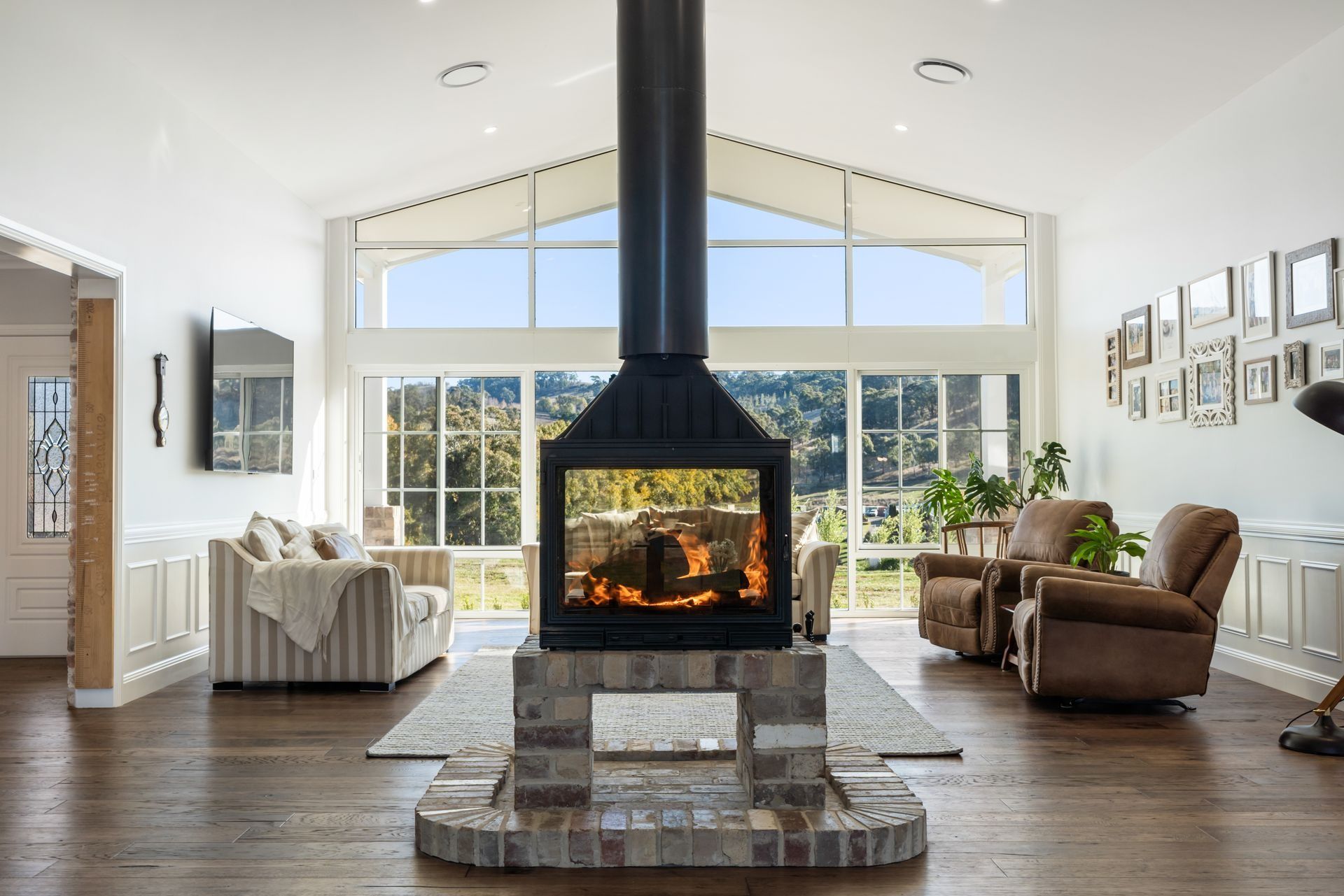 A Living Room With a Lit Fireplace, Armchairs — Climate King In Orange, NSW