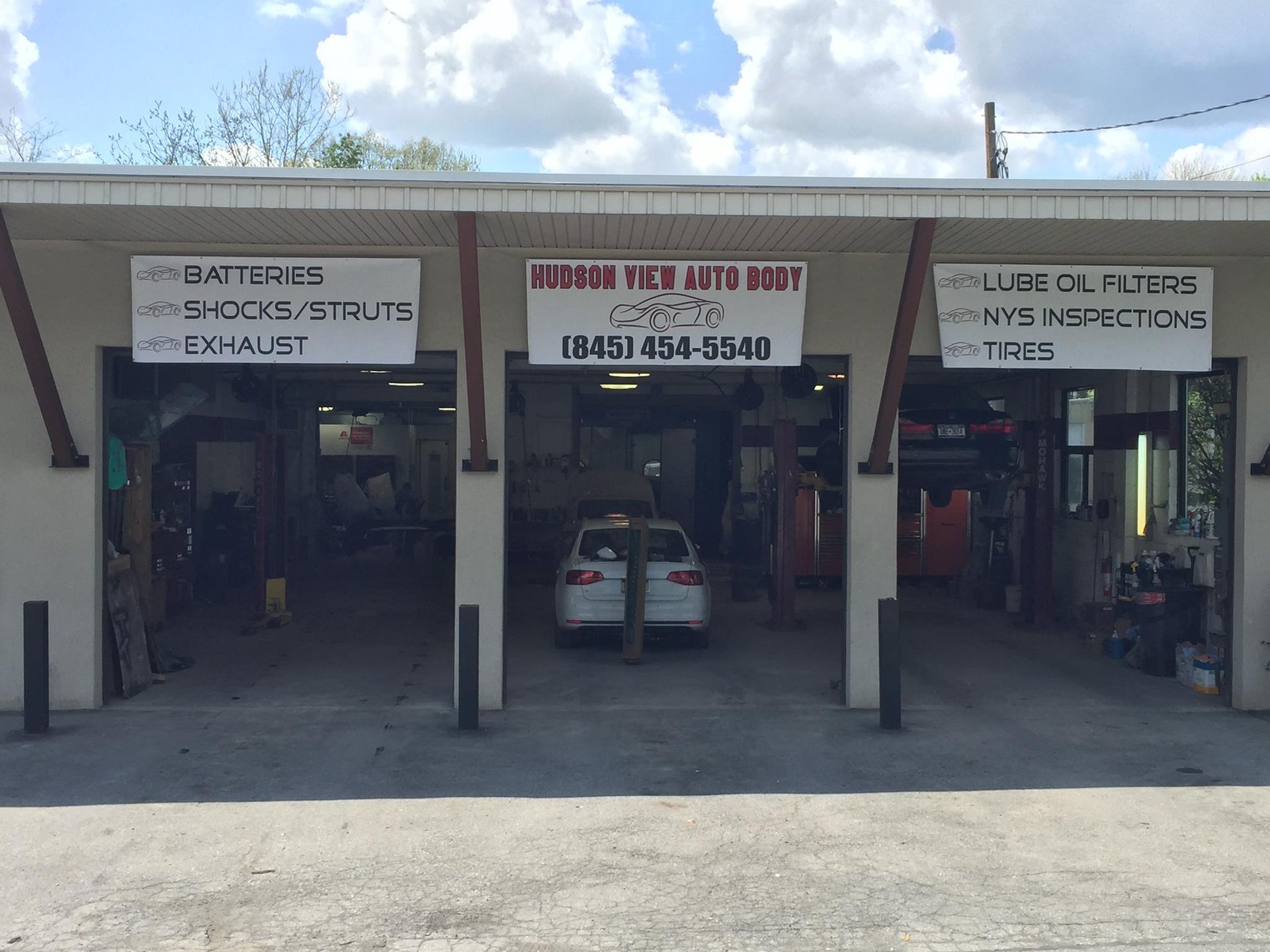 A three-bay auto repair shop exterior with service signs, including 