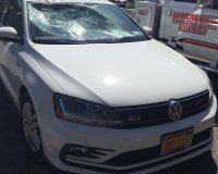 A white Volkswagen Jetta with a cracked windshield parked in an outdoor lot.