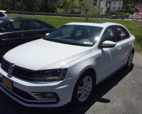 A white Volkswagen Jetta sedan parked in an outdoor lot on a sunny day.