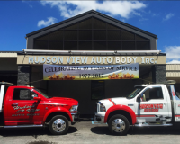 Hudson View Auto Body building with a banner celebrating 40 years of service, flanked by a red and a white tow truck.