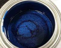 An open metal paint can filled with vibrant, deep blue metallic paint with a glossy finish.
