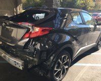 Black Toyota C-HR with significant rear-end damage, including a missing bumper and shattered rear windshield.
