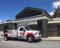 A white and red tow truck parked in front of a building with a banner for 