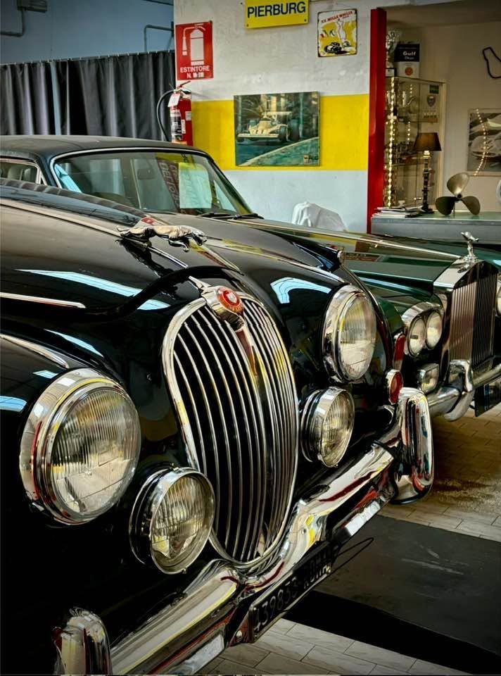 Berlina Jaguar d'epoca nera in un garage, con griglia e fari cromati.