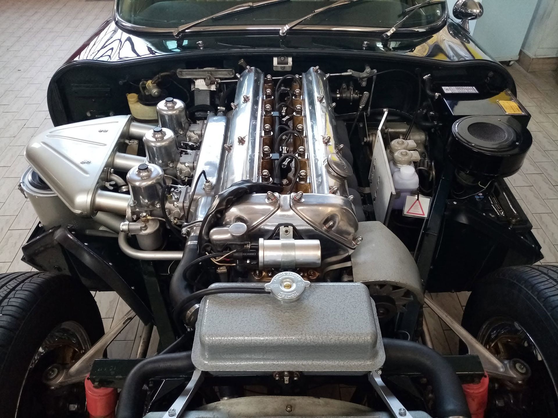 Vano motore aperto che mostra un grande motore V8 con collettore di aspirazione lucidato e componenti meccanici a vista.