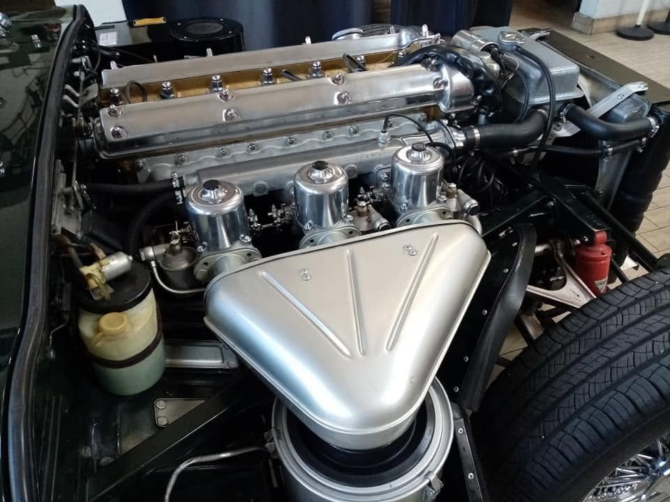 Primo piano di un motore di un'auto lucidato con presa d'aria cromata e componenti visibili nel vano motore.