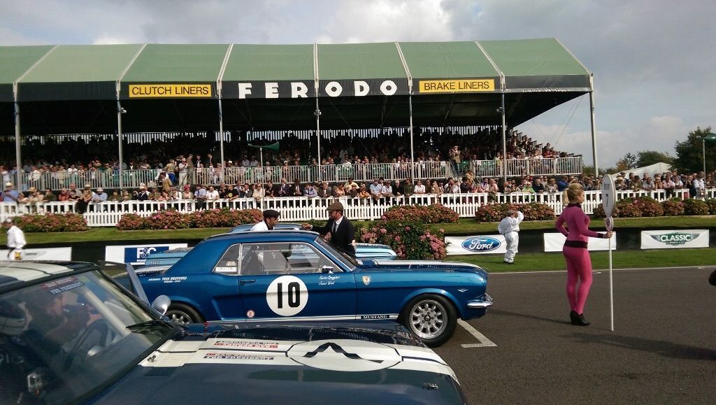 Un'auto da corsa blu con il numero 10 su una pista, con una folla e una tribuna sullo sfondo.