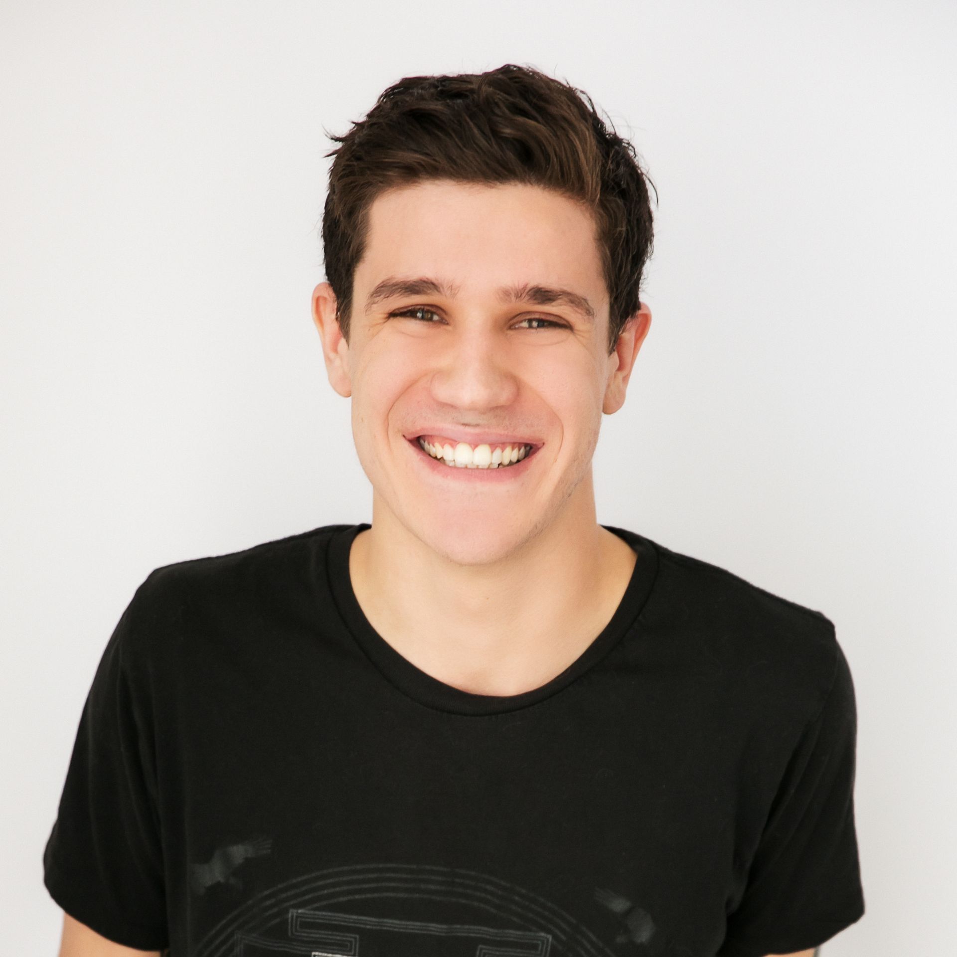 Smiling man in a black T-shirt against a plain light background