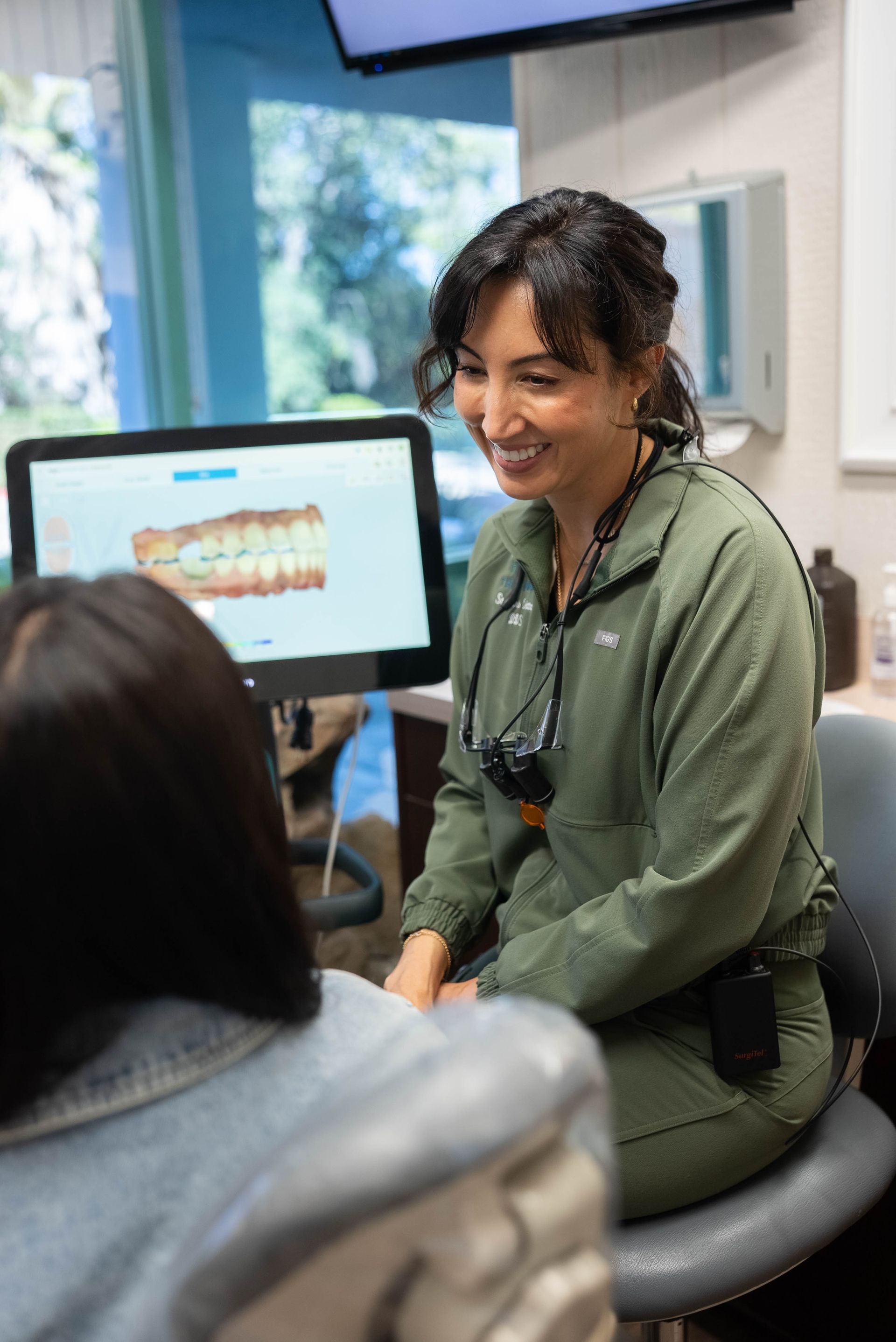 Dentist showing dental X-ray on a monitor to a seated patient in a clinic
