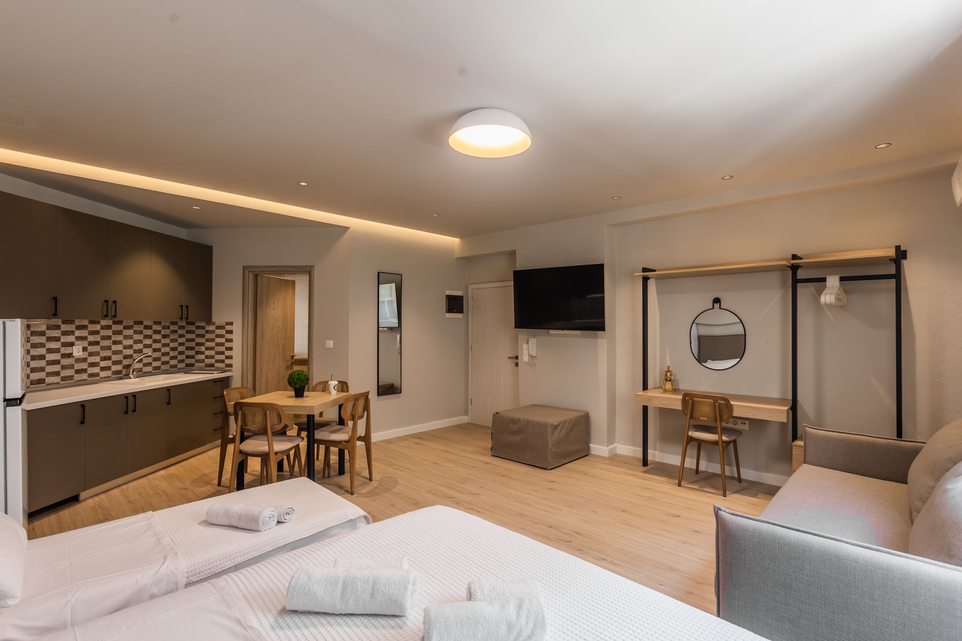 Studio apartment with kitchen, dining area, bed, couch, desk, and TV.