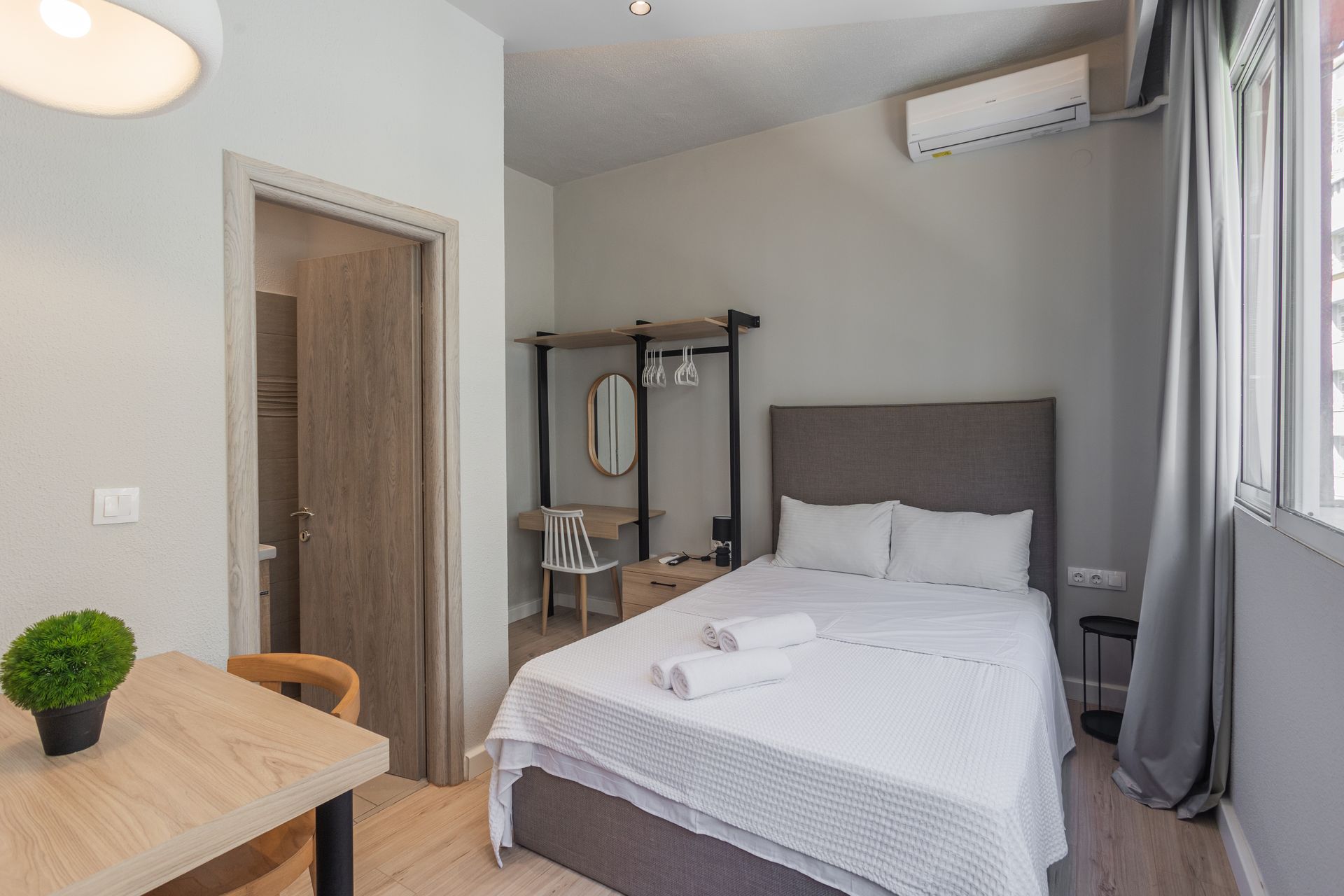 A small, tidy bedroom with a bed, desk, and a small bathroom visible.