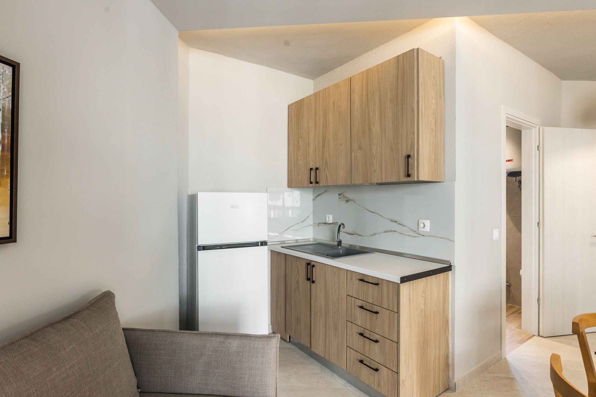 Small apartment kitchen with light wood cabinets, white refrigerator, and countertop.
