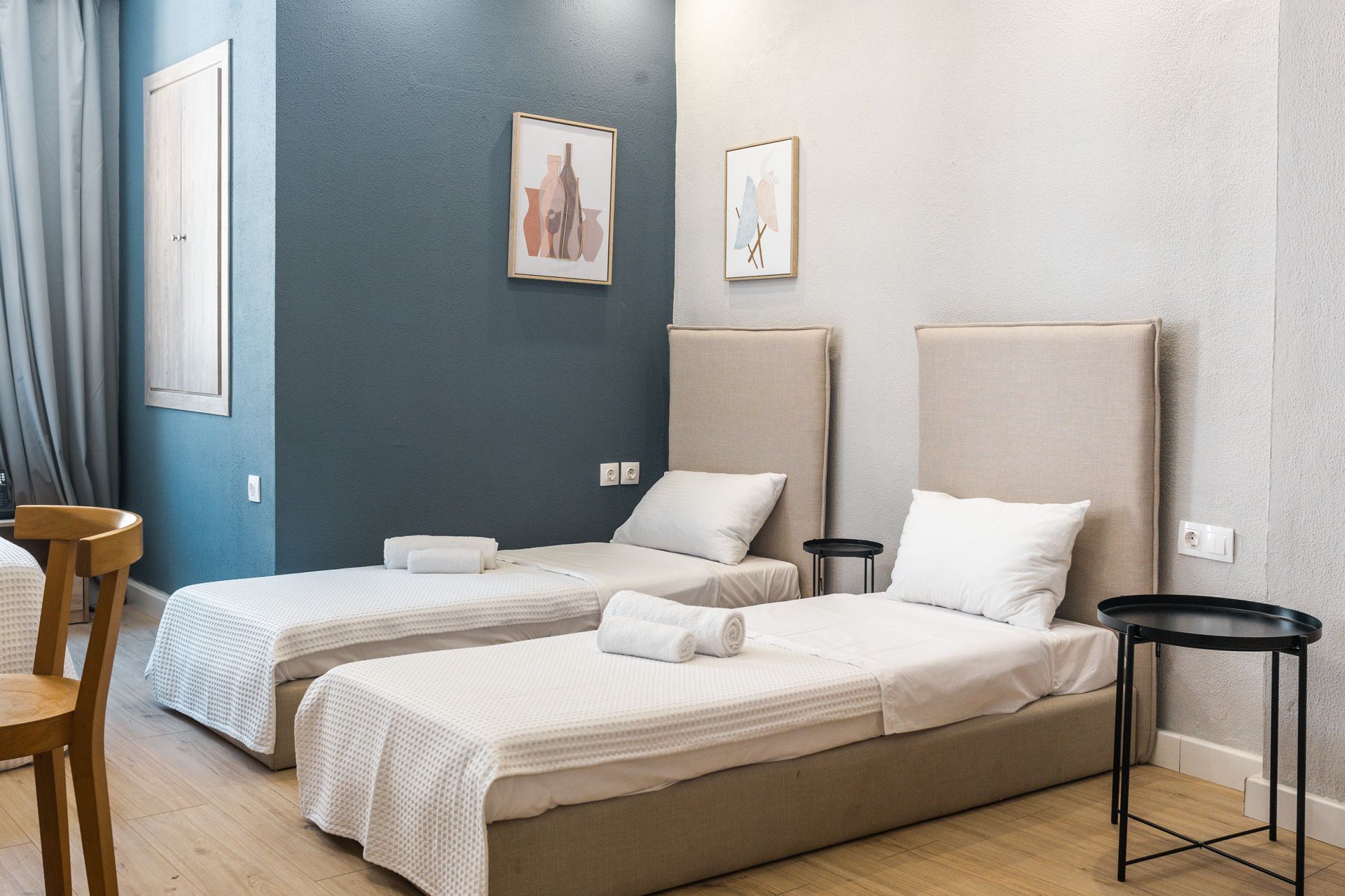 Two twin beds in a modern room with neutral walls, side tables, and artwork.