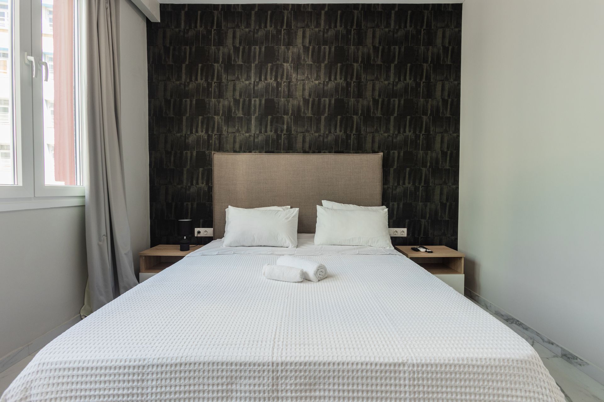 Bedroom with a bed, nightstands, and textured dark wall behind the headboard.