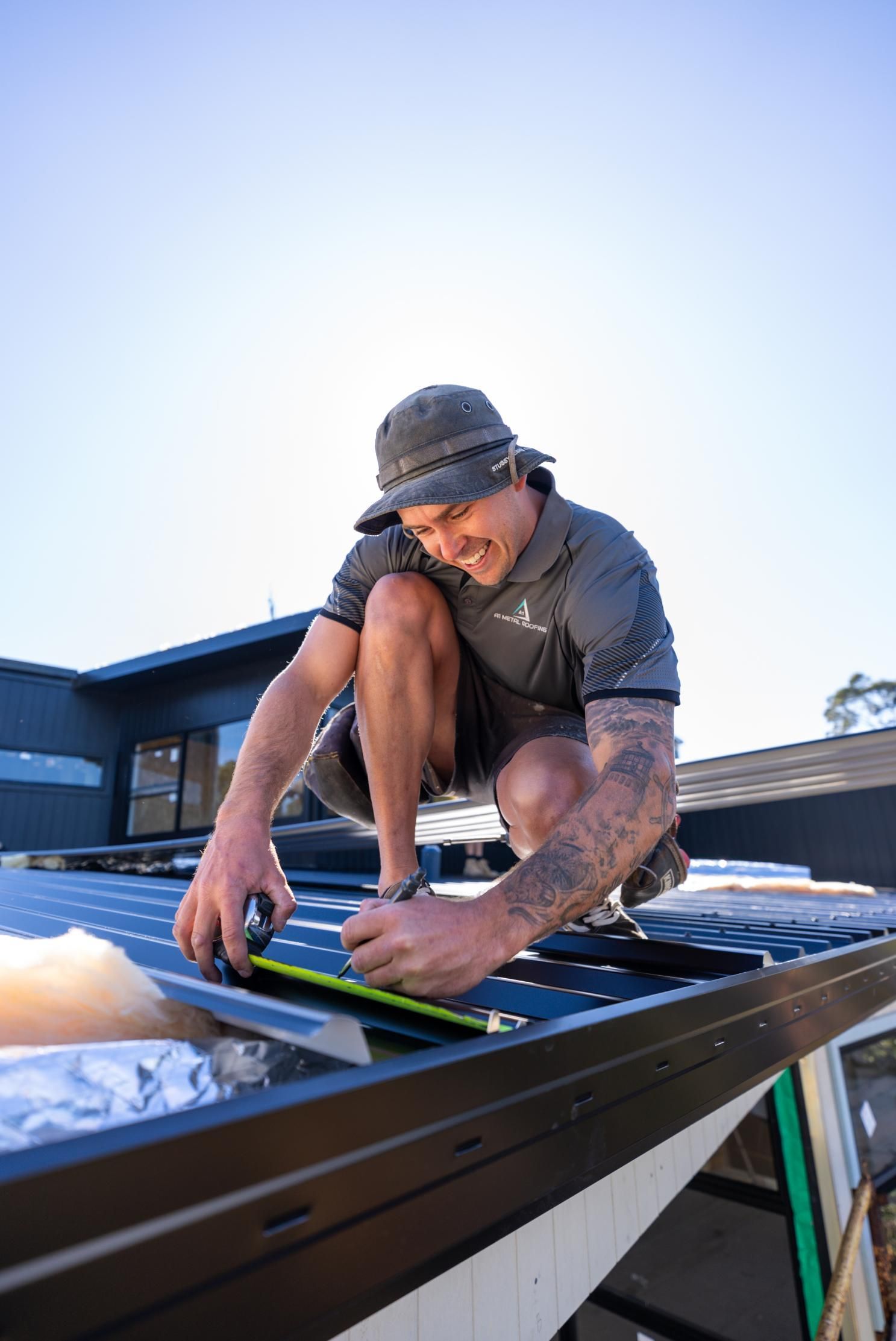A Man is Installing Solar Panels on The Roof of a House — Roofing Contractor in Wauchope, NSW