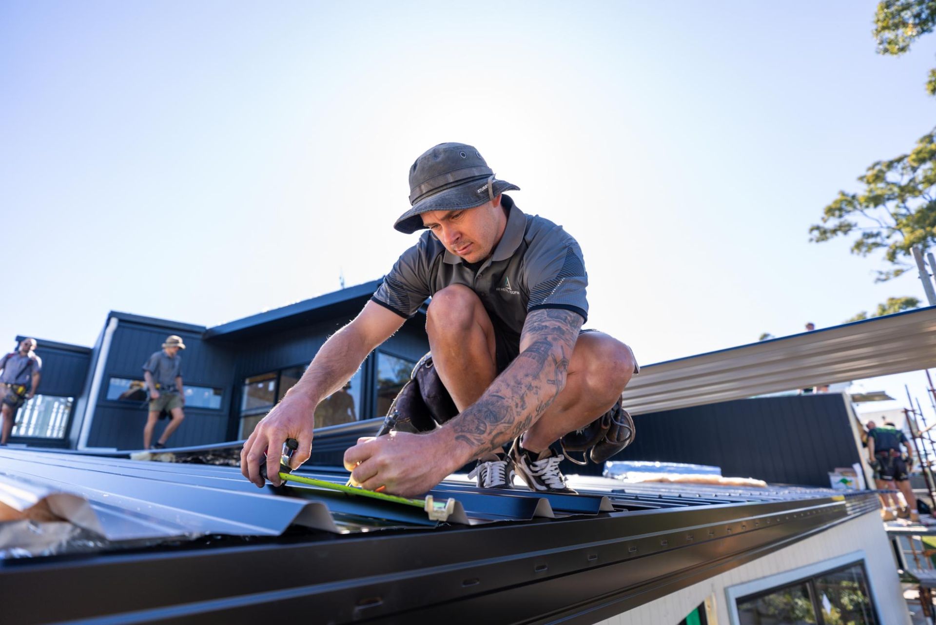 Man is Kneeling on the Top of a Roof Measuring a Piece of Metal — Roofing Contractor in Wauchope, NSW