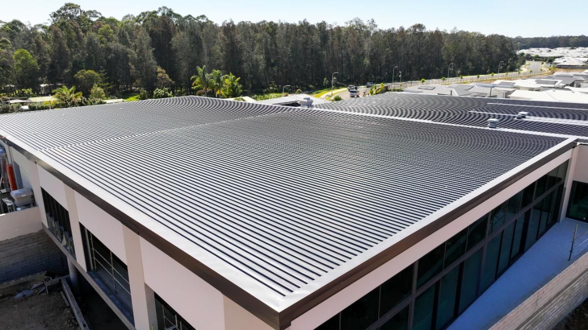 A Building With Solar Panel On The Roof — Roofing Contractor in Wauchope, NSW