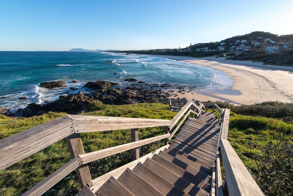 A Wooden Staircase Leading To a Beach With A Vie of Ocean — Roofing Contractor in Port Macquarie, NSW