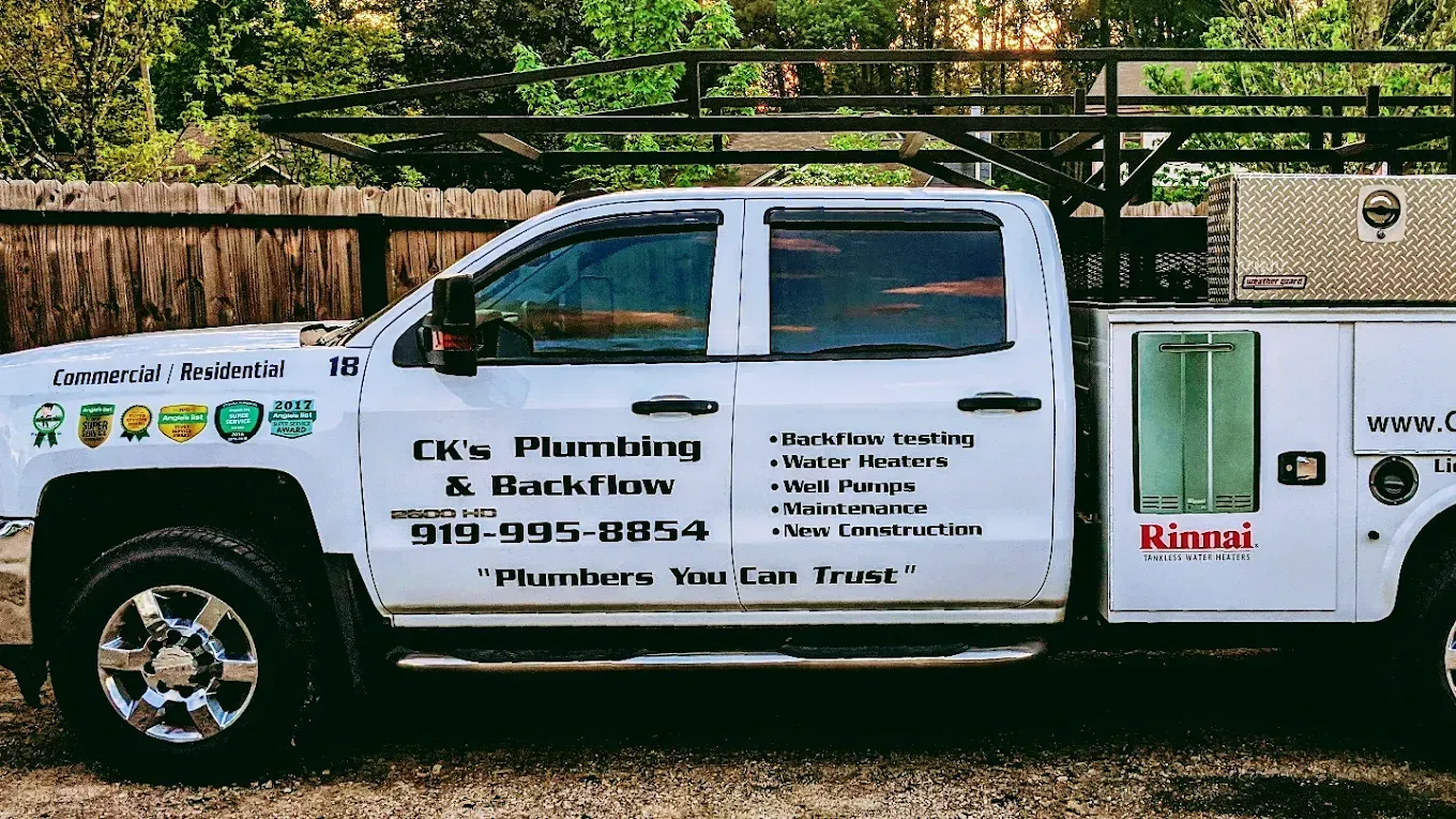 White pickup truck with business decals parked outdoors by a fence