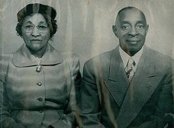Two formal portrait photos of a woman and a man in suits and glasses, side by side on a faded background
