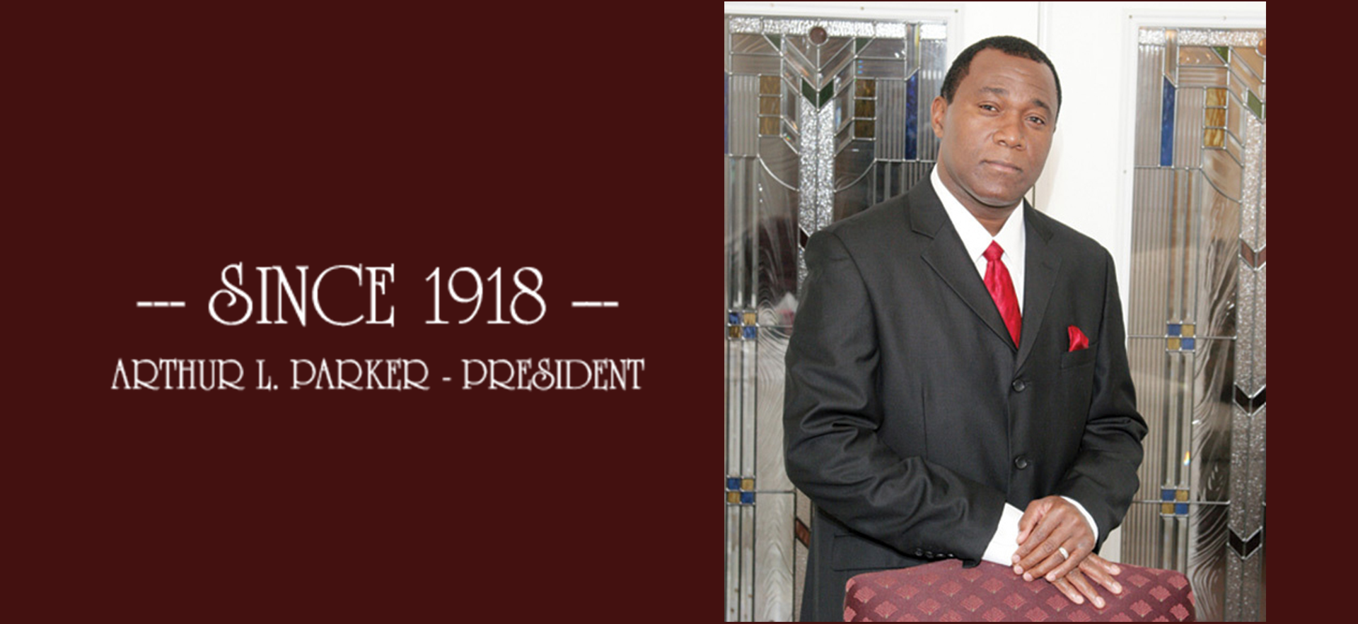 “Since 1918” banner beside a suited man standing indoors in front of clothing displays