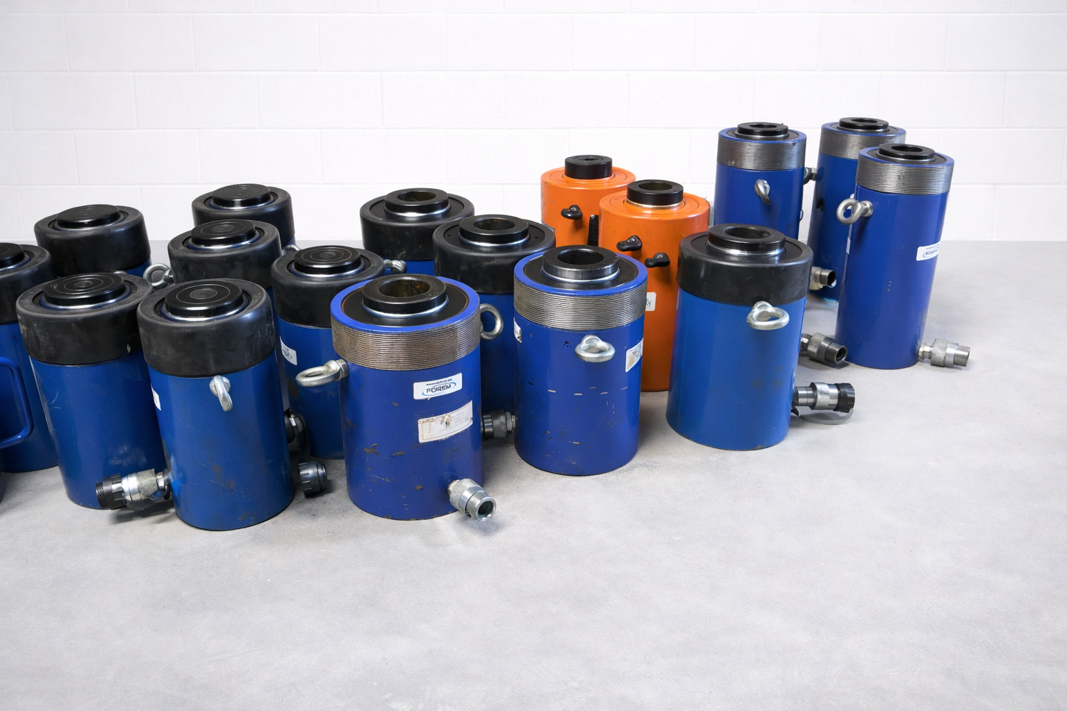 A collection of blue and orange industrial hydraulic cylinders of varying sizes arranged on a white surface.