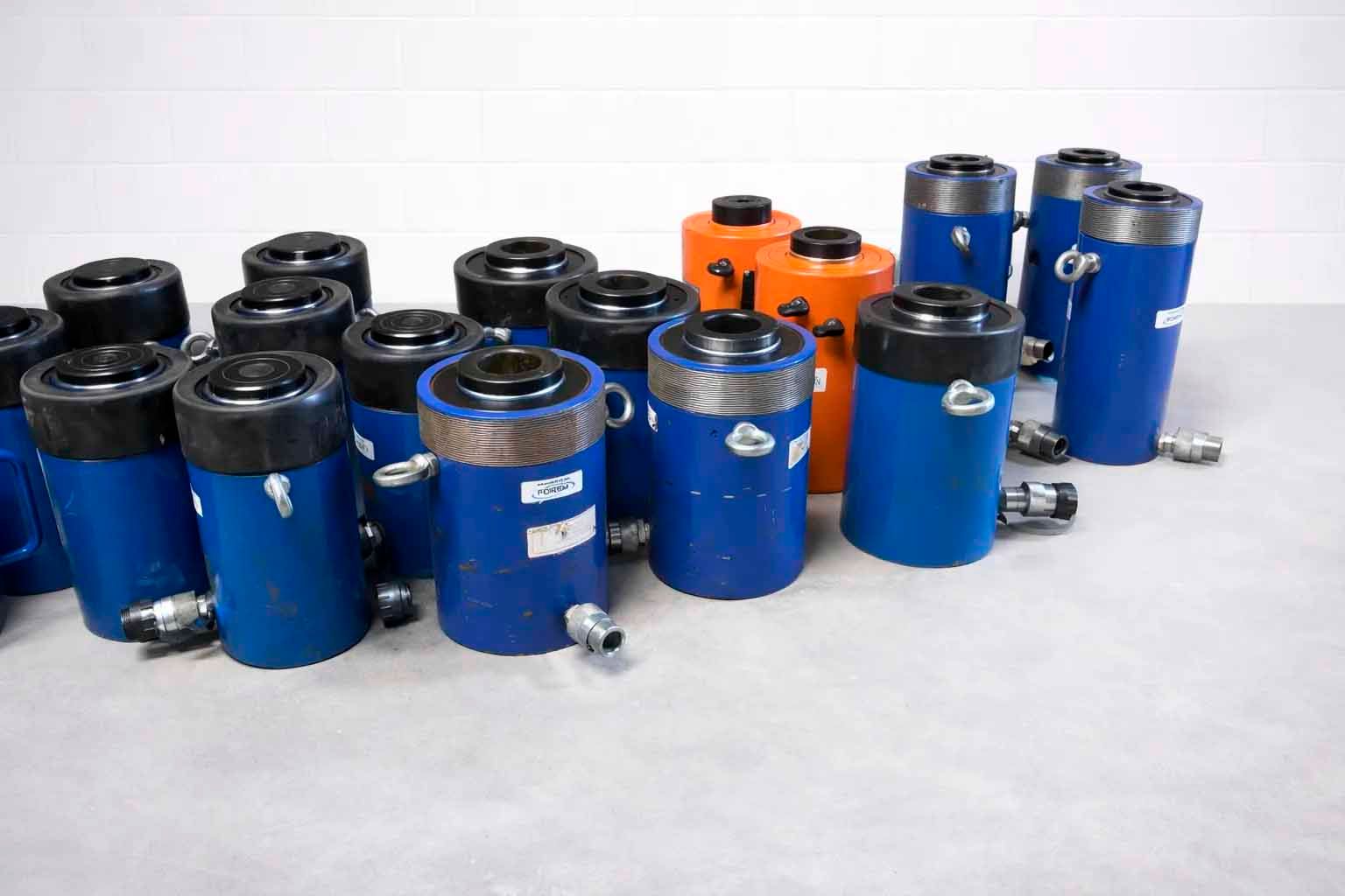 Blue and orange hydraulic cylinders on a white surface.