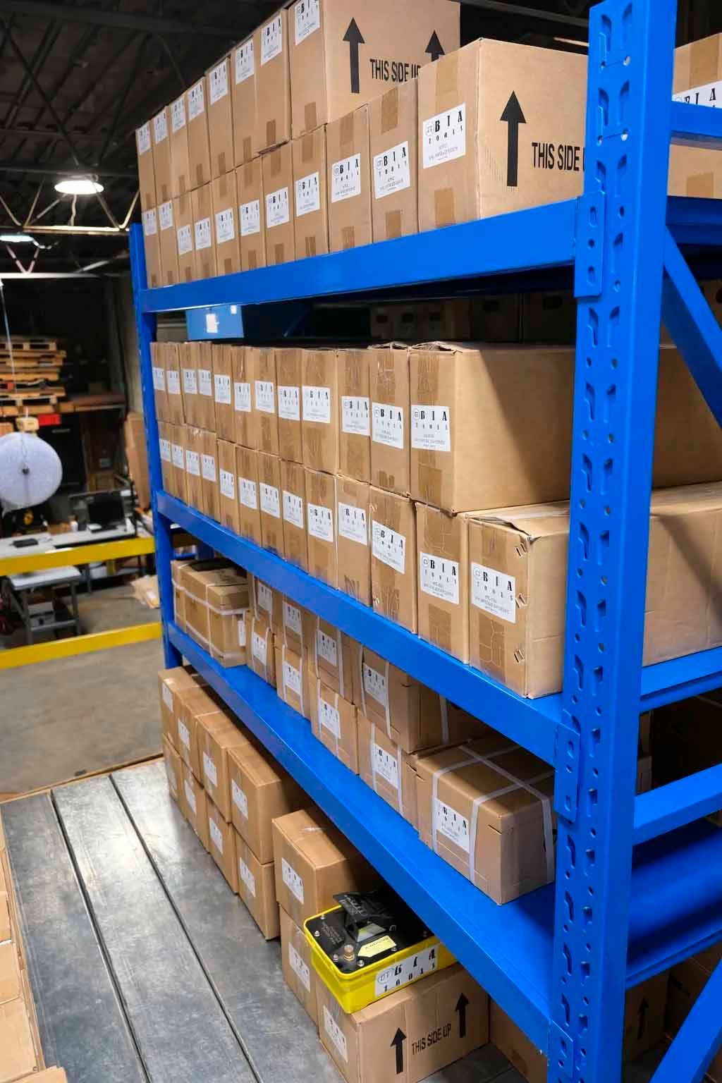 Blue metal shelves filled with cardboard boxes in a warehouse setting.