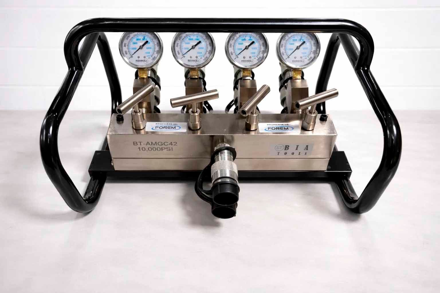 A pressure manifold with four gauges, valves, and a black protective frame.