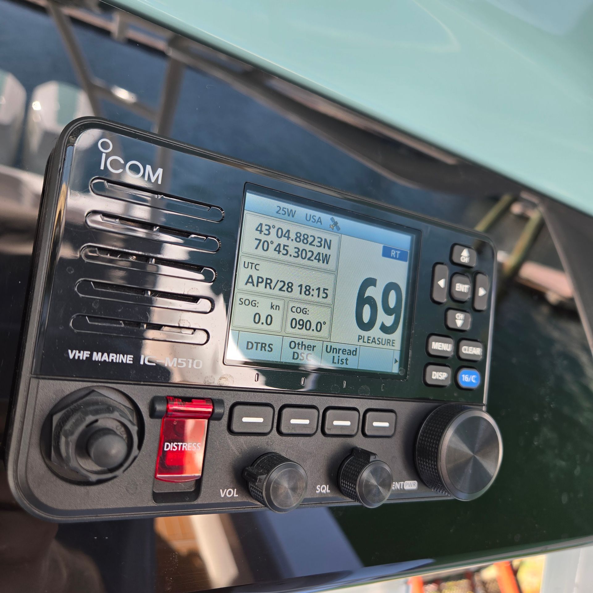 An Icom IC-M510 VHF marine radio mounted on a boat console, displaying GPS coordinates, time, and channel 69.