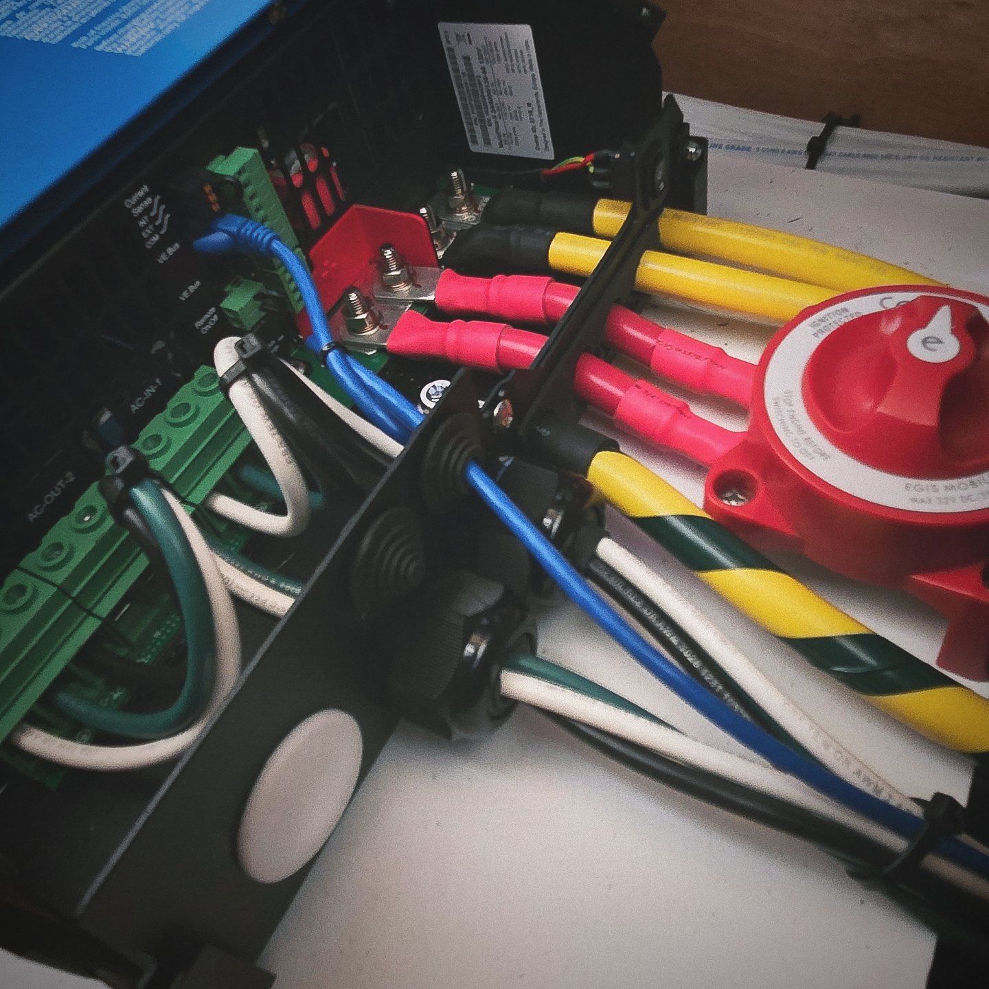 Victron MultiPlus-II inverter/charger unit mounted on a wooden wall with various electrical wiring and a red power switch.