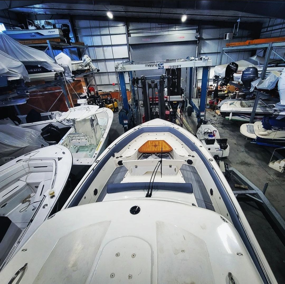 A high-angle view of a boat in a large, indoor storage facility filled with several other boats in various states of repair.
