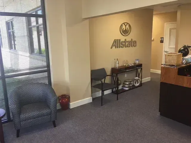 Allstate office waiting area with chair, table, and reception desk in beige and gray tones