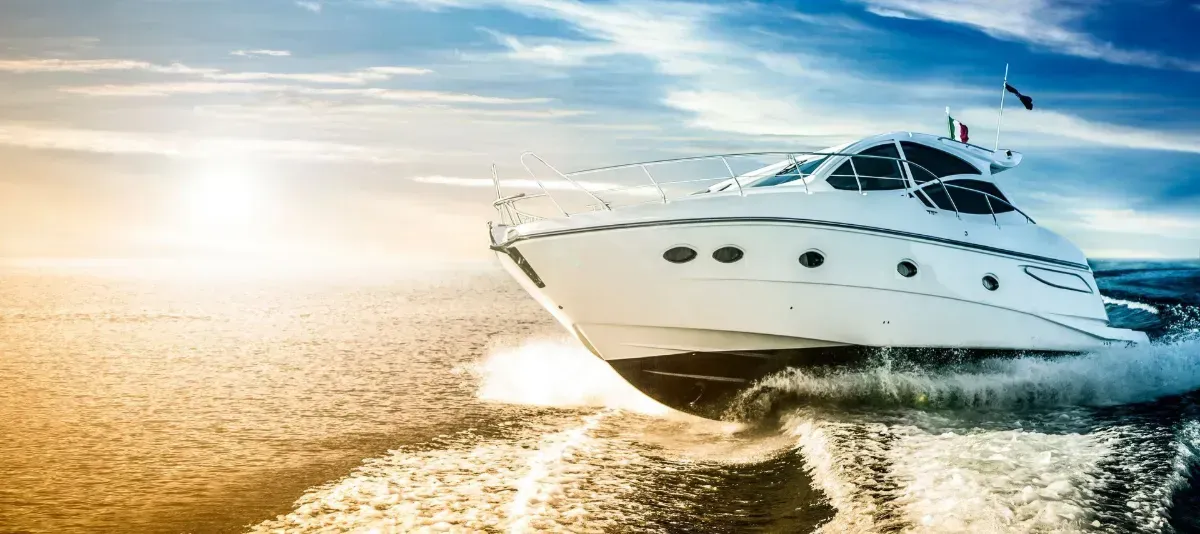 White speedboat skims across golden water at sunset, leaving a foamy wake.
