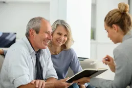 Three people in a bright office reviewing a document and smiling during a meeting