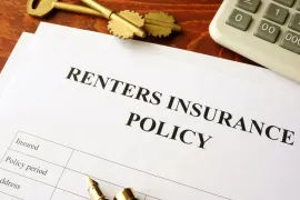 Renters insurance policy document on a desk with calculator, pen, and keys