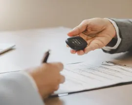 Business meeting with hands passing a small device over documents beside a laptop on a desk