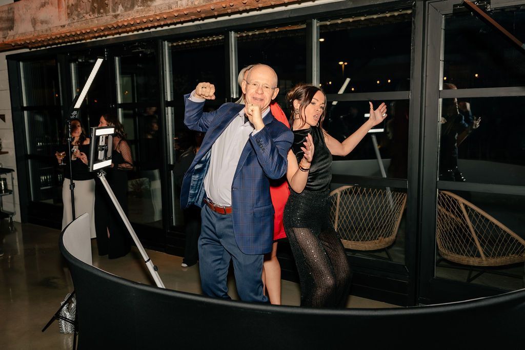 Guests dancing inside a 360 photo booth setup at an event, with LED lighting and a mounted camera capturing the moment.