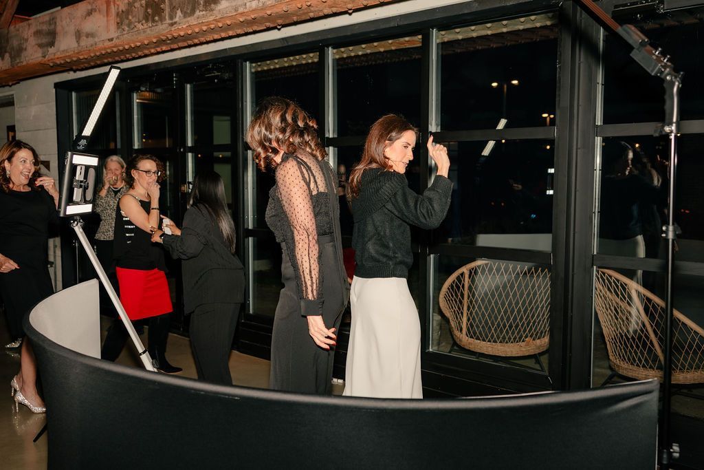 Guests pose and dance inside a 360 photo booth setup during a party